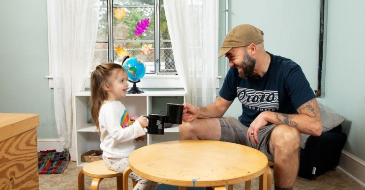 Head Roaster Tony of Red Rooster Coffee Roasters sits with his daughter at a child-size table, clinking coffee mugs.